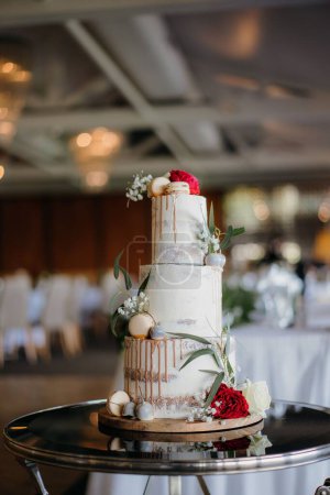Foto de Un plano vertical de un hermoso pastel de boda en capas con macarrones y flores - Imagen libre de derechos