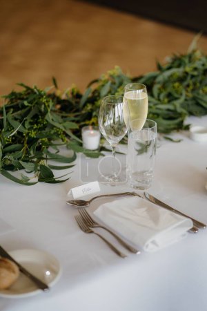 Foto de Una toma vertical de copas de champán, servilletas y tenedores en la mesa blanca - Imagen libre de derechos