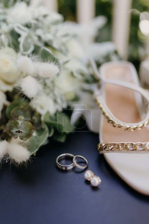 Foto de Un plano vertical de elegantes anillos de boda, zapatos y otros accesorios - Imagen libre de derechos
