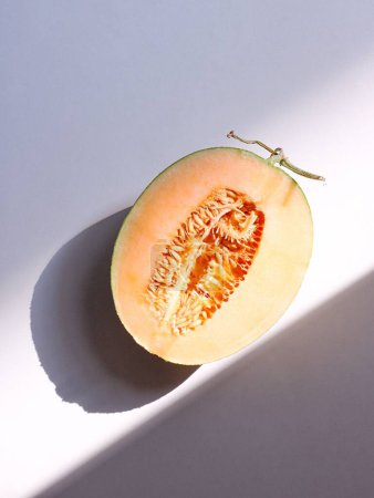 Photo for A top view of a half of cantaloupe isolated on blue  background with a shadow - Royalty Free Image