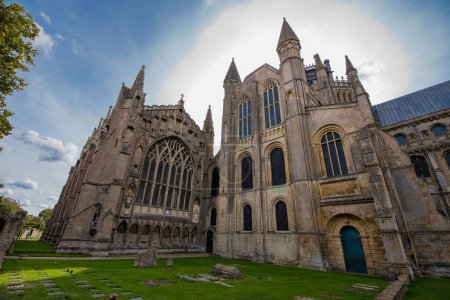 Foto de Una hermosa escena de la Catedral de Ely con estilo gótico rodeado de árboles y hierba verde durante el día en Chapter House, The College, Reino Unido - Imagen libre de derechos