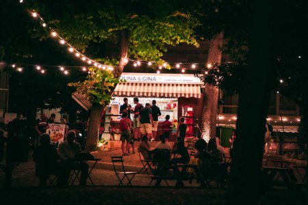Foto de Un pequeño quiosco de comida iluminada con una multitud de personas por la noche en Laquila, Italia - Imagen libre de derechos