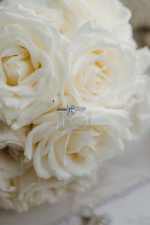 Foto de Un plano vertical de un anillo de bodas en las rosas blancas - Imagen libre de derechos