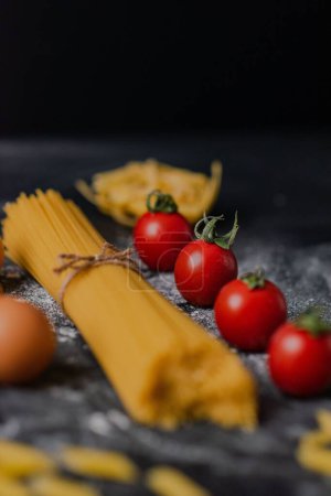Téléchargez les photos : Un gros plan de pâtes crues sur une table dans un restaurant avec des œufs et des tomates cerises autour - en image libre de droit