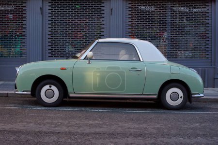 Photo for Side view of Nissan Figaro parked on a street in Bray, Ireland. Car produced in Japan in 1991, with emerald green exterior color symbolizing spring. - Royalty Free Image