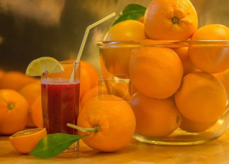 Photo for A composition with oranges in bowl and outside and  a glass with blood orange juice next to it - Royalty Free Image