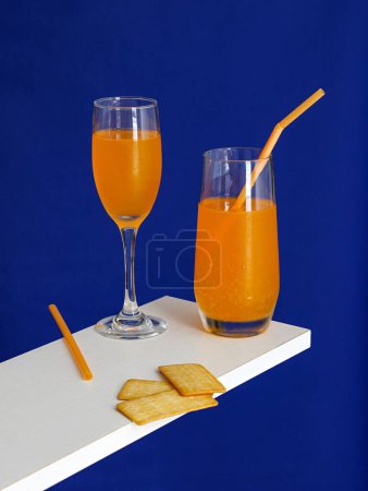Photo for Two cups of Mimosa Cocktail drinks and Cracker Biscuit isolated on blue background - Royalty Free Image