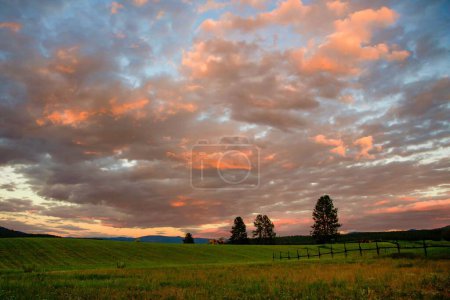 Foto de Una vista panorámica de un campo verde bajo un cielo nublado al atardecer en Montana, EE.UU. - Imagen libre de derechos