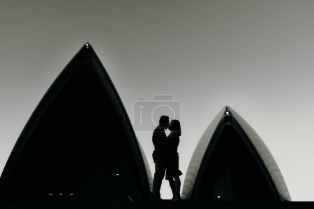 Téléchargez les photos : Un cliché en niveaux de gris d'une silhouette de couple sur fond de bâtiments modernes - en image libre de droit