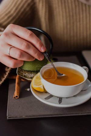Téléchargez les photos : Un plan vertical d'une main féminine agitant son thé dans un café - en image libre de droit