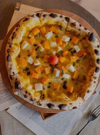 Foto de Un primer plano de pizza con verduras en una tabla de madera, periódicos alrededor - Imagen libre de derechos