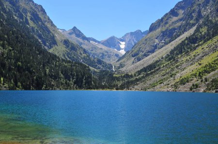 Foto de Una vista panorámica de un lago rodeado de verdes montañas en un día soleado - Imagen libre de derechos