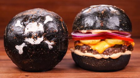 Foto de Un primer plano de una hamburguesa negra hecha de un bollo crujiente contra el fondo aislado - Imagen libre de derechos