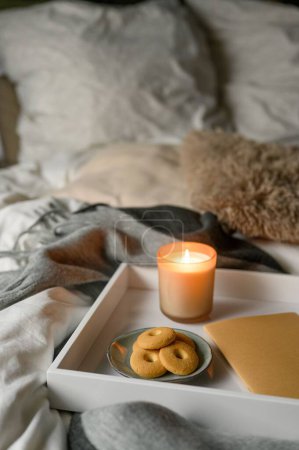 Téléchargez les photos : Composition d'automne confortable avec bougie, biscuits, cahier et crayon dans un lit confortable - en image libre de droit