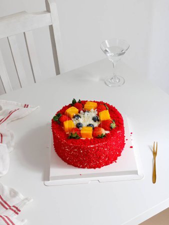 Foto de Un tiro vertical de pastel de terciopelo rojo decorado con bayas en la mesa blanca - Imagen libre de derechos