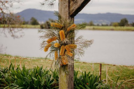 Photo for A closeup shot of a wooden pole with dry floral decorations near the water - Royalty Free Image