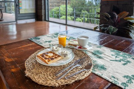 Téléchargez les photos : Un petit déjeuner rustique confortable dans le café sur une table en bois avec gaufres, jus de fruits et café - en image libre de droit