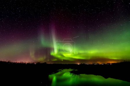 Photo for A beautiful shot of polar lights against a dark starry night sky over a lake - Royalty Free Image