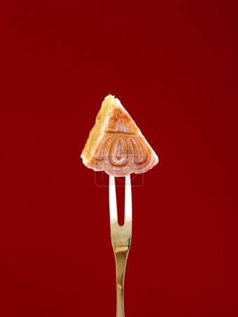Photo for A closeup of a tiny cookie slice with a floral ornament stamp on a maroon background - Royalty Free Image