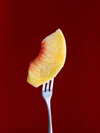 Photo for A closeup of a peach slice on a fork in a maroon background - Royalty Free Image