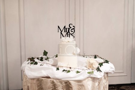 Téléchargez les photos : Un beau gâteau de mariage à deux niveaux avec Mr & Mrs topper décoré de fleurs - en image libre de droit