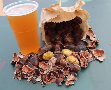 Photo for A closeup of a bag of roasted chestnuts with beer - Royalty Free Image