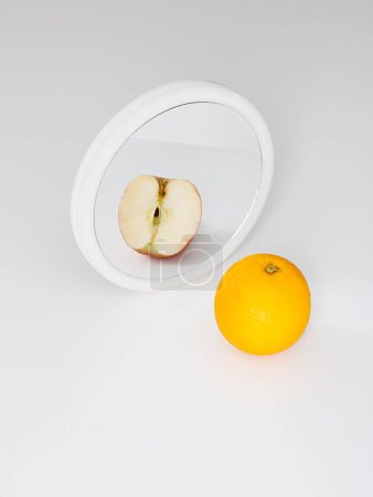 Téléchargez les photos : Plan vertical d'une orange réfléchissante dans un miroir comme une pomme rouge coupée - en image libre de droit
