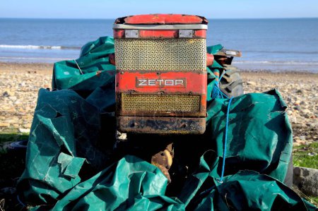 Téléchargez les photos : Un tracteur Zetor de l'ère communiste tchèque sur la plage de Saltburn enveloppé de peaux de pétrole vertes - en image libre de droit