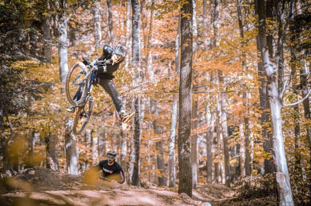 Photo for A horizontal action shot of two men in Holeshotpunx black sportswear shredding local trails in autumn - Royalty Free Image