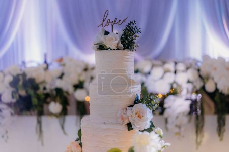 Téléchargez les photos : Un beau gâteau de mariage à trois niveaux avec Love topper décoré de fleurs - en image libre de droit