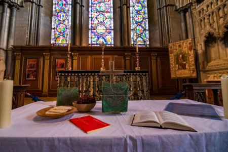 Foto de Una escena del interior de lujo de una iglesia con ventanas medievales y libros sagrados, una cruz y decoraciones sobre la mesa - Imagen libre de derechos
