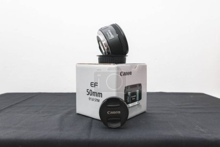 Photo for A Canon 50mm 1.8 STM Lens on its box on a black table - Royalty Free Image