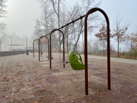 Foto de Un parque abandonado con columpios vacíos durante el día en un día nublado de otoño - Imagen libre de derechos