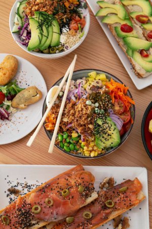 Photo for A vertical top view of poke bowls and fish with vegetables on a wooden table - Royalty Free Image