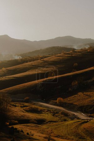 Téléchargez les photos : Un haut-angle d'un paysage d'automne avec des vallées jaunes ensoleillées, des montagnes brumeuses et un ciel clair en arrière-plan - en image libre de droit
