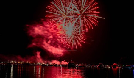 Téléchargez les photos : Une belle vue de nuit de feux d'artifice rouges dans le ciel noir sur la ville illuminant skyline - en image libre de droit