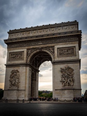 Téléchargez les photos : L'extérieur de l'Arc de Triomphe sous un ciel nuageux spectaculaire à Paris, France - en image libre de droit