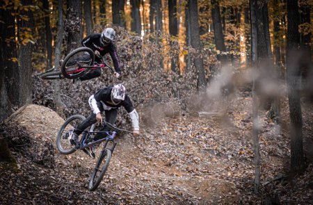 Photo for The two men riding bicycles in a horizontal action view while wearing Holeshotpunx black clothes and helmets - Royalty Free Image