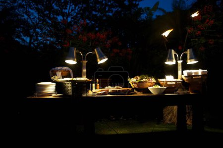 Photo for An outdoor balcony table with food and illuminated lamps - Royalty Free Image