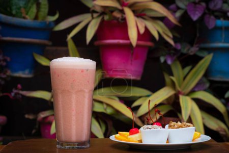 Photo for A closeup of a glass of a strawberry milkshake served with a plate of fruits and pastry - Royalty Free Image
