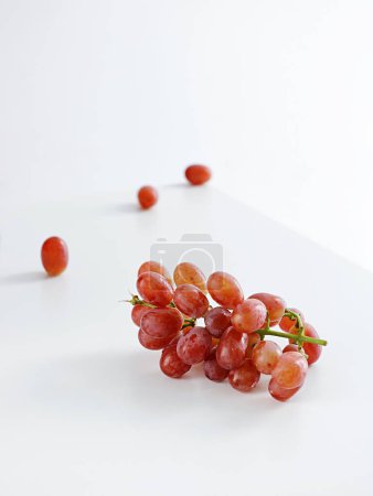 Téléchargez les photos : Plan vertical d'un bouquet de raisin rouge sur une table blanche - en image libre de droit