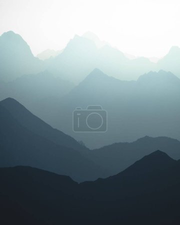 Téléchargez les photos : Un plan vertical des silhouettes bleutées des montagnes au soleil. - en image libre de droit
