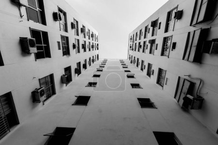 Téléchargez les photos : Plan bas-angle en niveaux de gris d'un immeuble résidentiel sous un ciel nuageux. - en image libre de droit