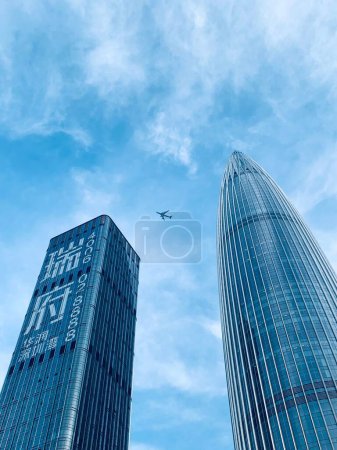 Téléchargez les photos : Plan vertical à angle bas d'un avion volant parmi les gratte-ciel de Shenzhen, en Chine. - en image libre de droit