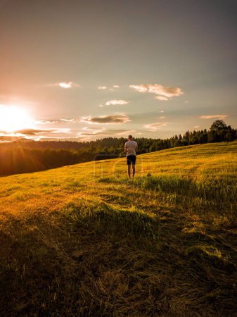 Téléchargez les photos : Plan vertical d'un jeune homme seul dans un champ rural au coucher du soleil dans le nord de la Norvège - en image libre de droit