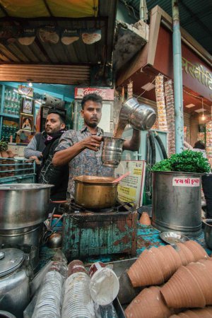 Photo for A vertical shot of a Chaiwala selling fresh mint masala chai in the very early hours of the morning in the small temple - Royalty Free Image
