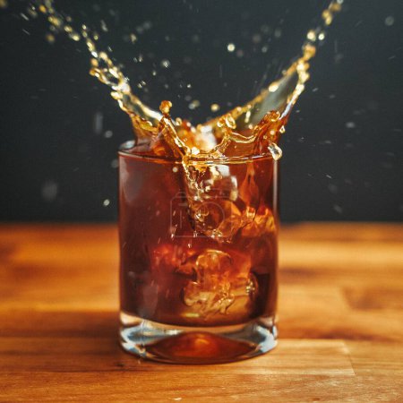 Photo for A closeup shot of ice splashing into a glass of brown coffee - Royalty Free Image