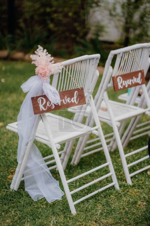 Photo for A vertical shot of decorative reserved chairs at an outdoor wedding - Royalty Free Image