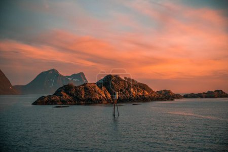 Foto de Un fascinante disparo de la puesta de sol sobre el mar con rocas montañosas y nubes dispersas - Imagen libre de derechos