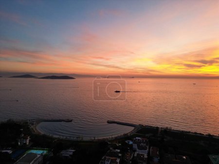 Foto de Una puesta de sol dorada sobre el océano cerca de los edificios - Imagen libre de derechos